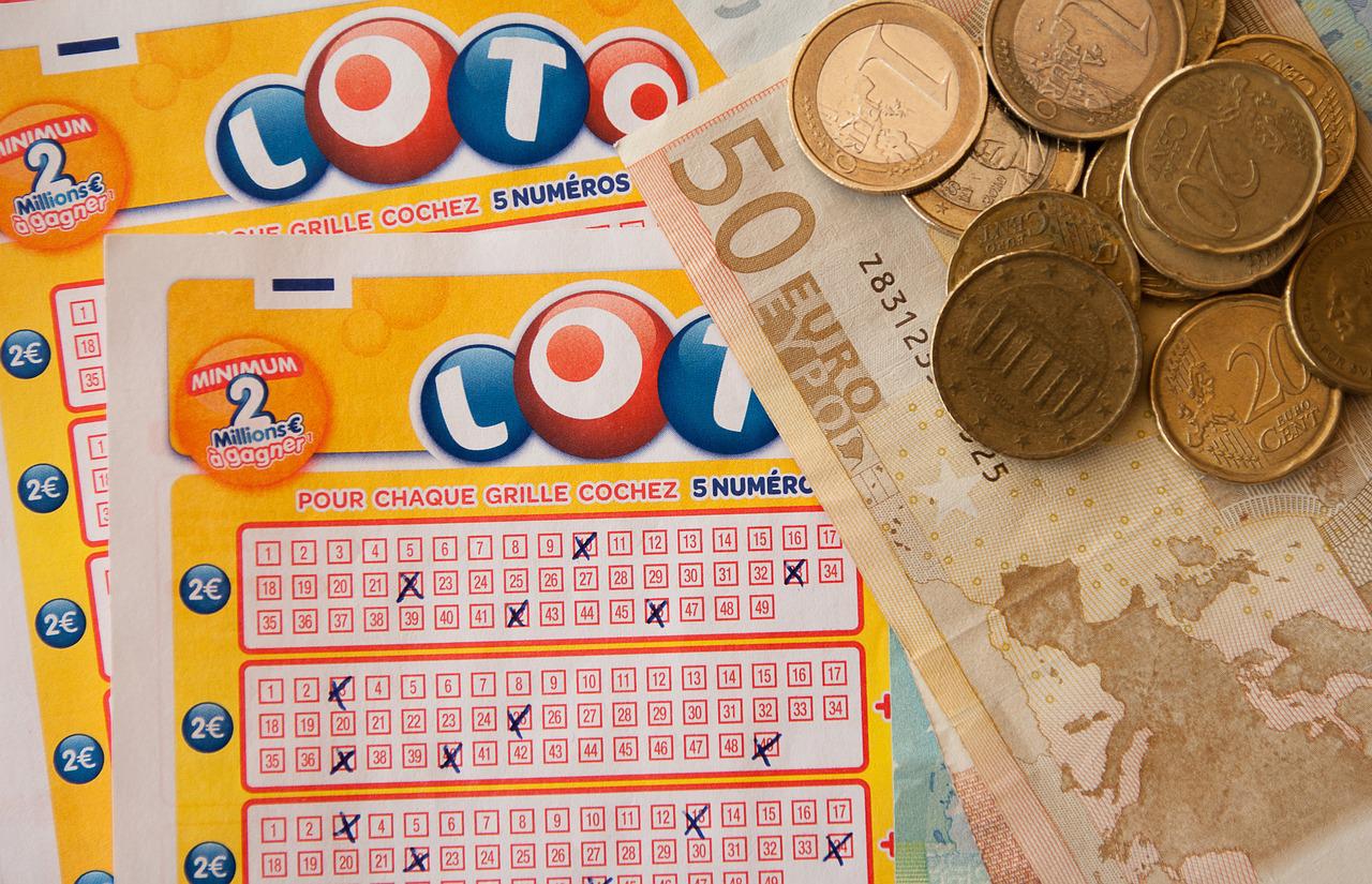 ausgefüllte Lottoscheine und Bargeld in Euro-Währung liegen zusammen nebeneinander